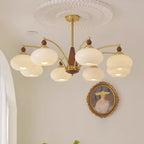 Clérachic Wood and Brass Chandelier in white, eight shades spreading soft cream light across a pale wall.