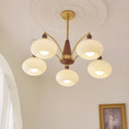 Clérachic Wood and Brass Chandelier in opal white, five shades lighting a room hung with a gilt frame.
