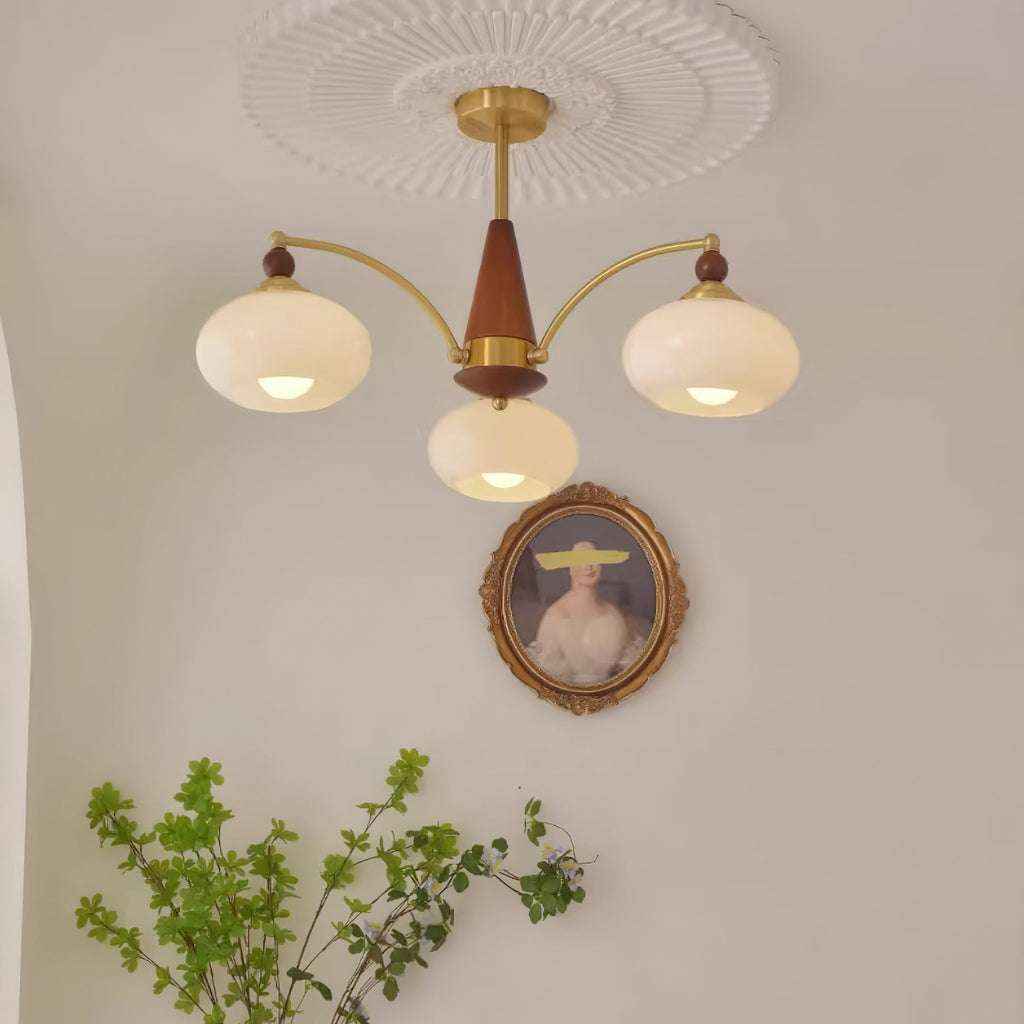 Clérachic Wood and Brass Chandelier in white glass, three shades lit above a portrait and a sprig of greenery.