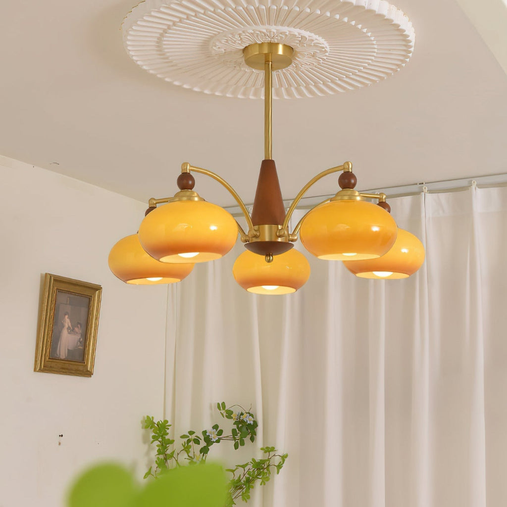 Clérachic Wood and Brass Chandelier in caramel glass, five lit shades over a curtained corner of a room.