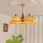 Clérachic Wood and Brass Chandelier in caramel glass, five lit shades over a curtained corner of a room.