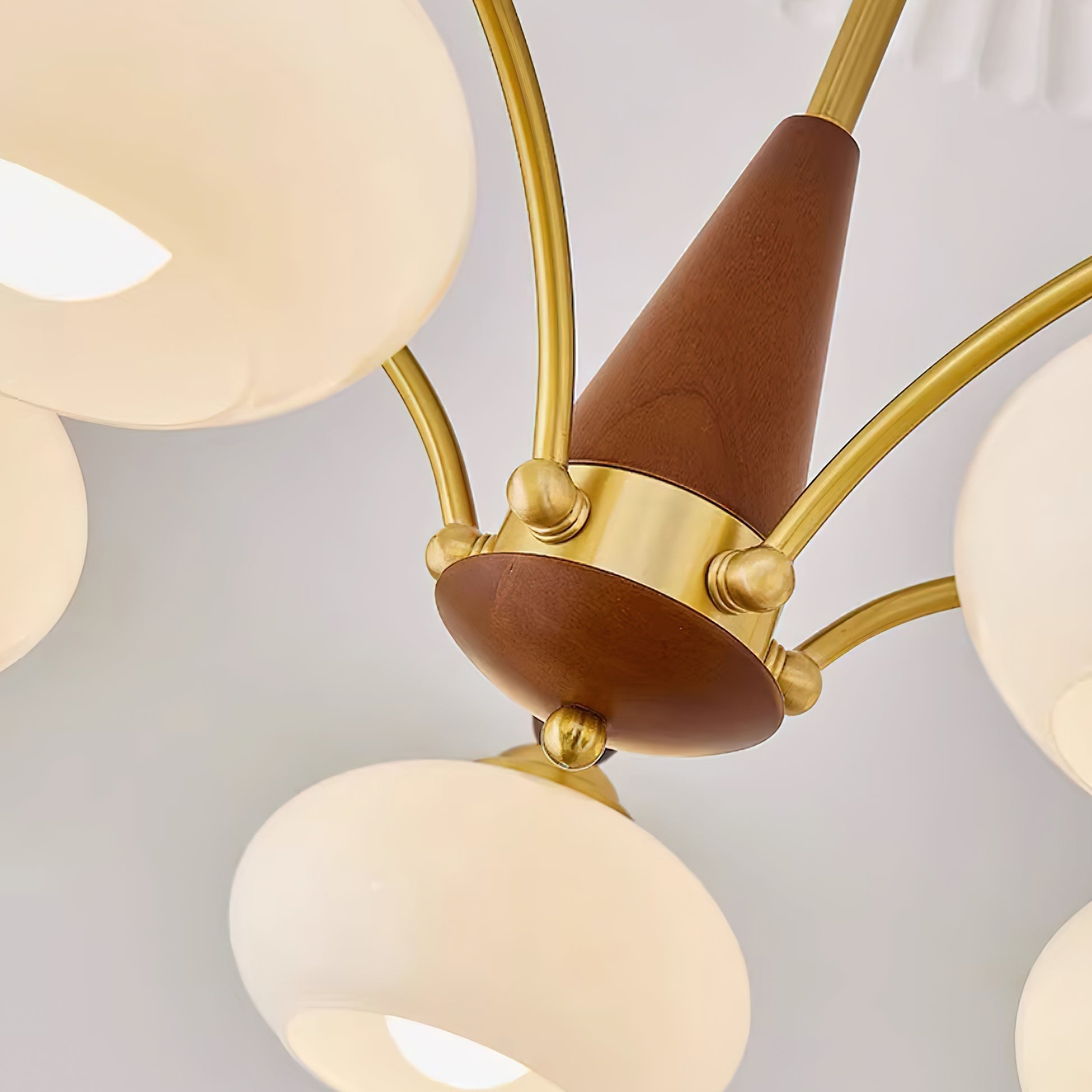 Turned wood cone hub of the Clérachic Wood and Brass Chandelier, with brass arms curving out to each shade.