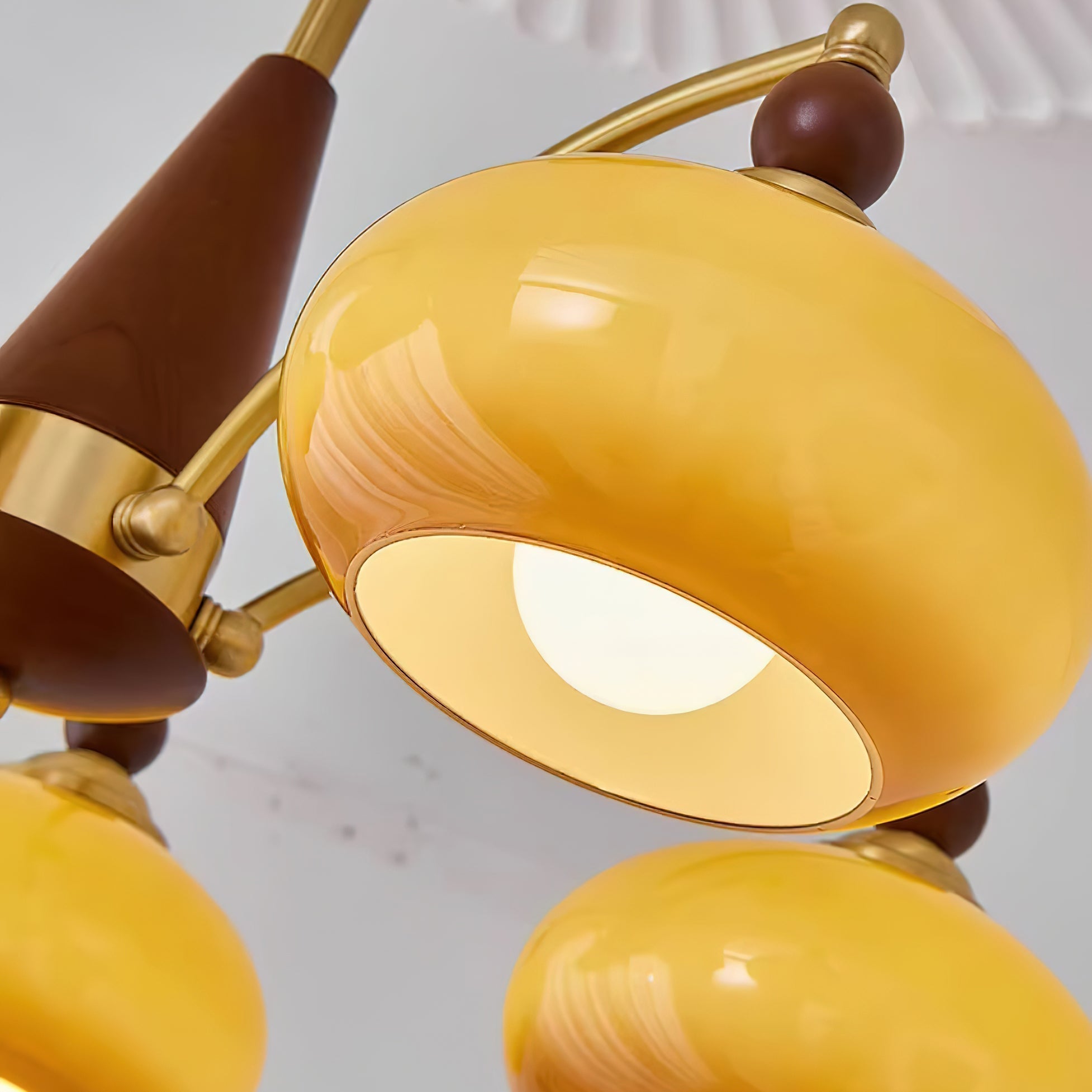One lit caramel shade of the Clérachic Wood and Brass Chandelier, showing the glossy swirl in the pressed glass.