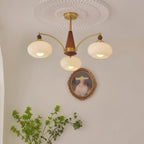 Clérachic three-light Wood and Brass Chandelier in white glass, lit above a small oval portrait.
