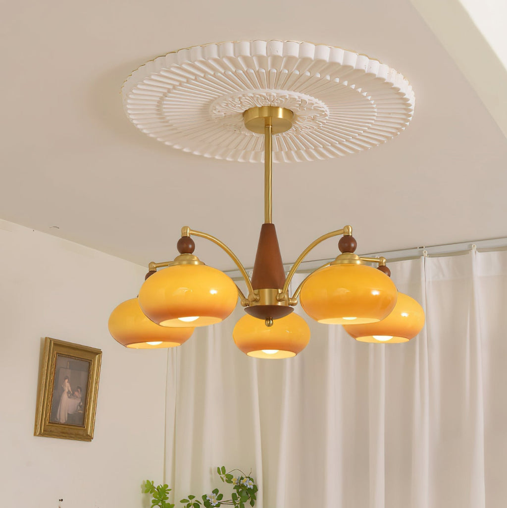 Clérachic five-light Wood and Brass Chandelier in amber, lighting a room hung with a gold-framed painting.