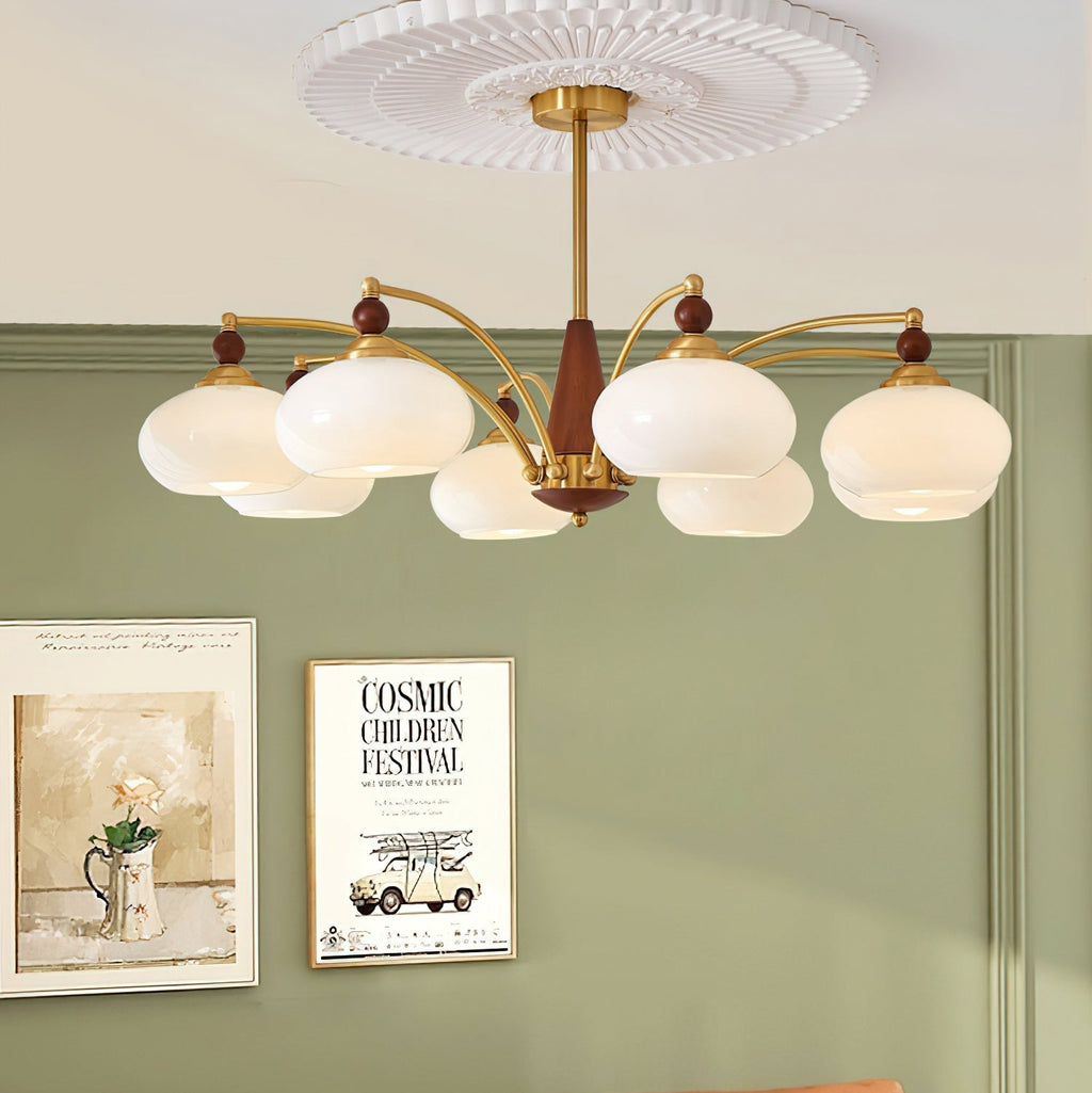Clérachic eight-light Wood and Brass Chandelier in white glass, hung before a sage wall and framed prints.