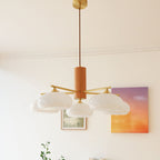 The five-light Clérachic wood and brass chandelier in white glass, hung from its brass canopy above framed wall art.