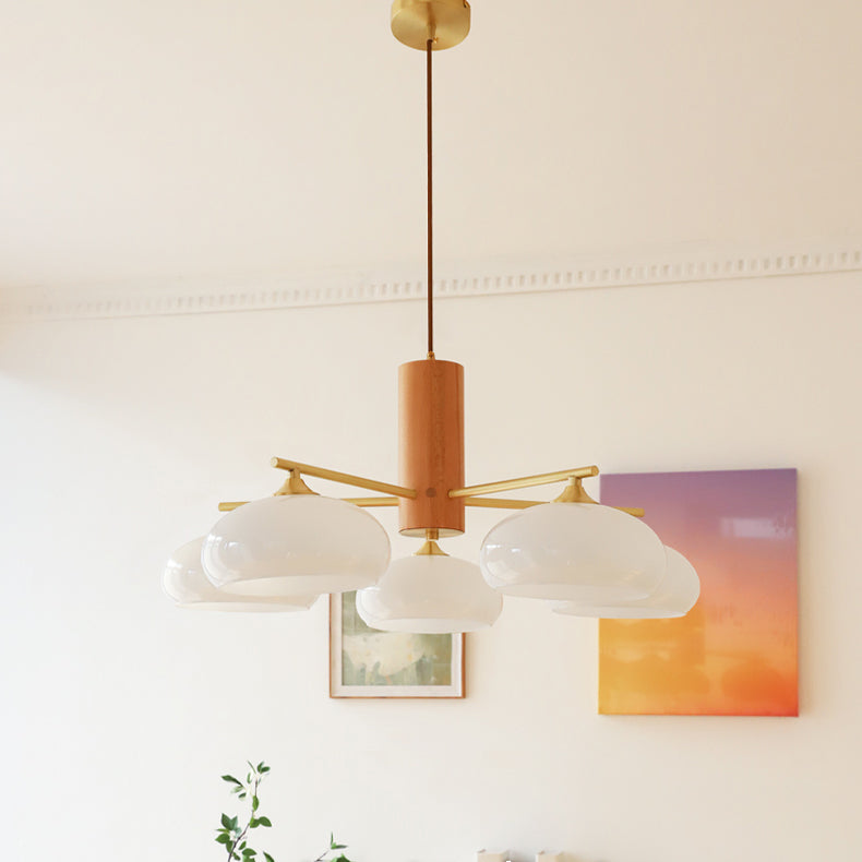 The five-light Clérachic wood and brass chandelier in white glass, hung from its brass canopy above framed wall art.