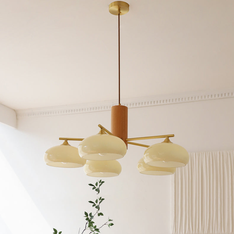 Clérachic chandelier in beige glass with five staggered shades, seen from below in a room corner with cornice and curtain.