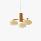 Studio view of the three-light Clérachic chandelier, beige glass discs on brass rods through a turned wood cylinder.