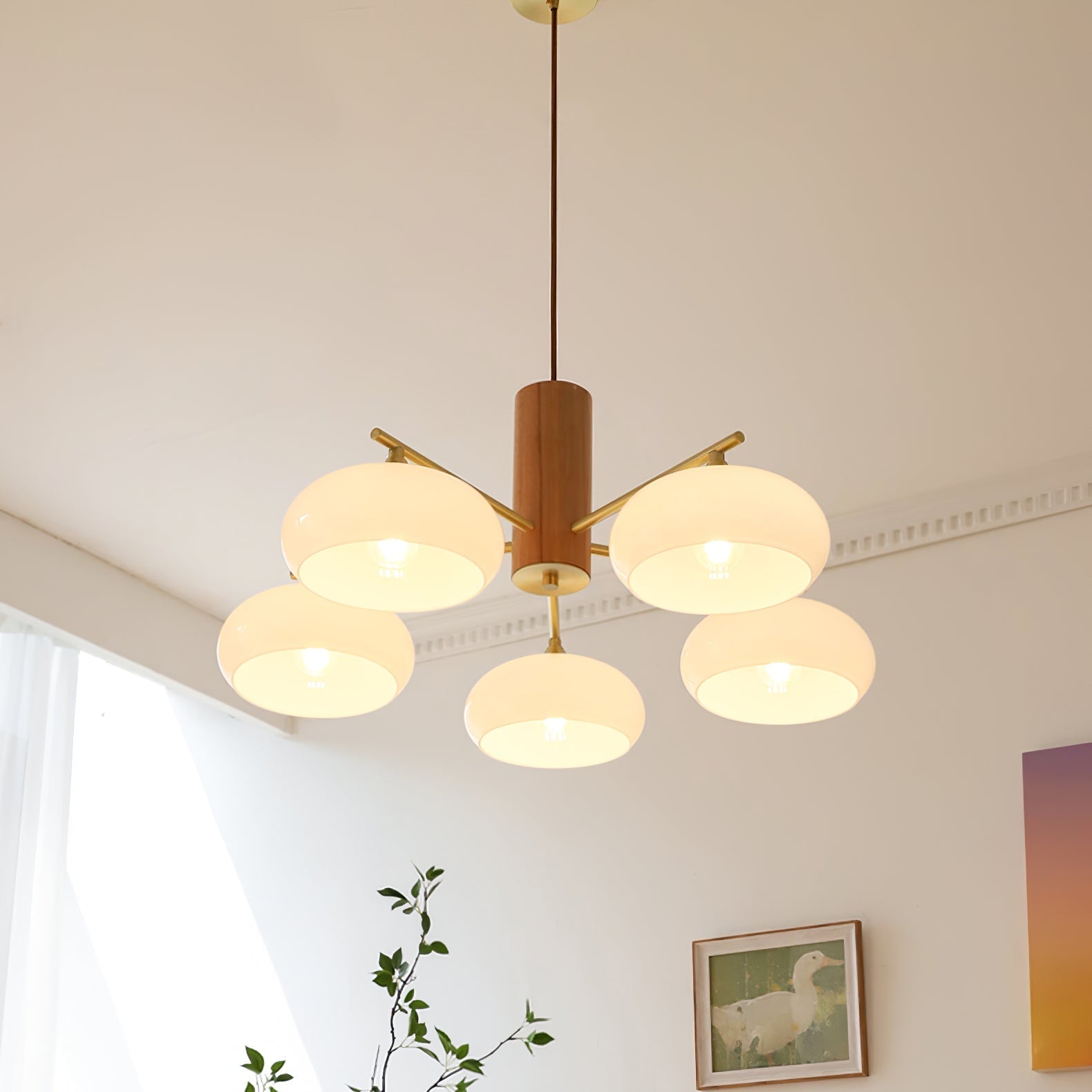 The Clérachic five-light chandelier lit near a sunlit window, white shades above a framed duck painting.