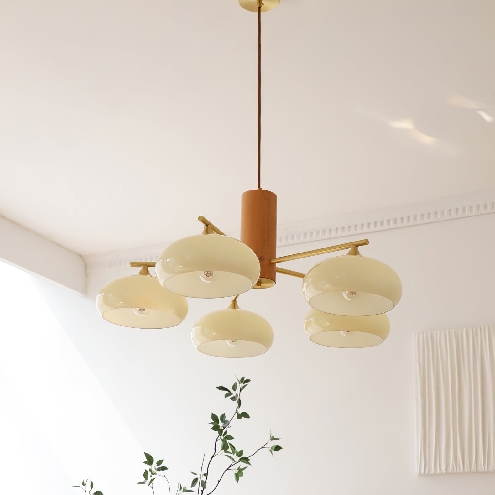 Warm evening light from the beige glass shades of the Clérachic chandelier beside a pleated wall hanging.