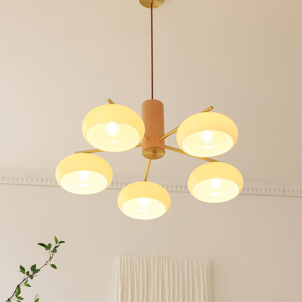 Five lit beige shades of the Clérachic chandelier hang level below a moulded cornice in a living room.