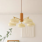 The Clérachic chandelier in beige glass, lit above a pleated white wall panel and a gilt picture frame.