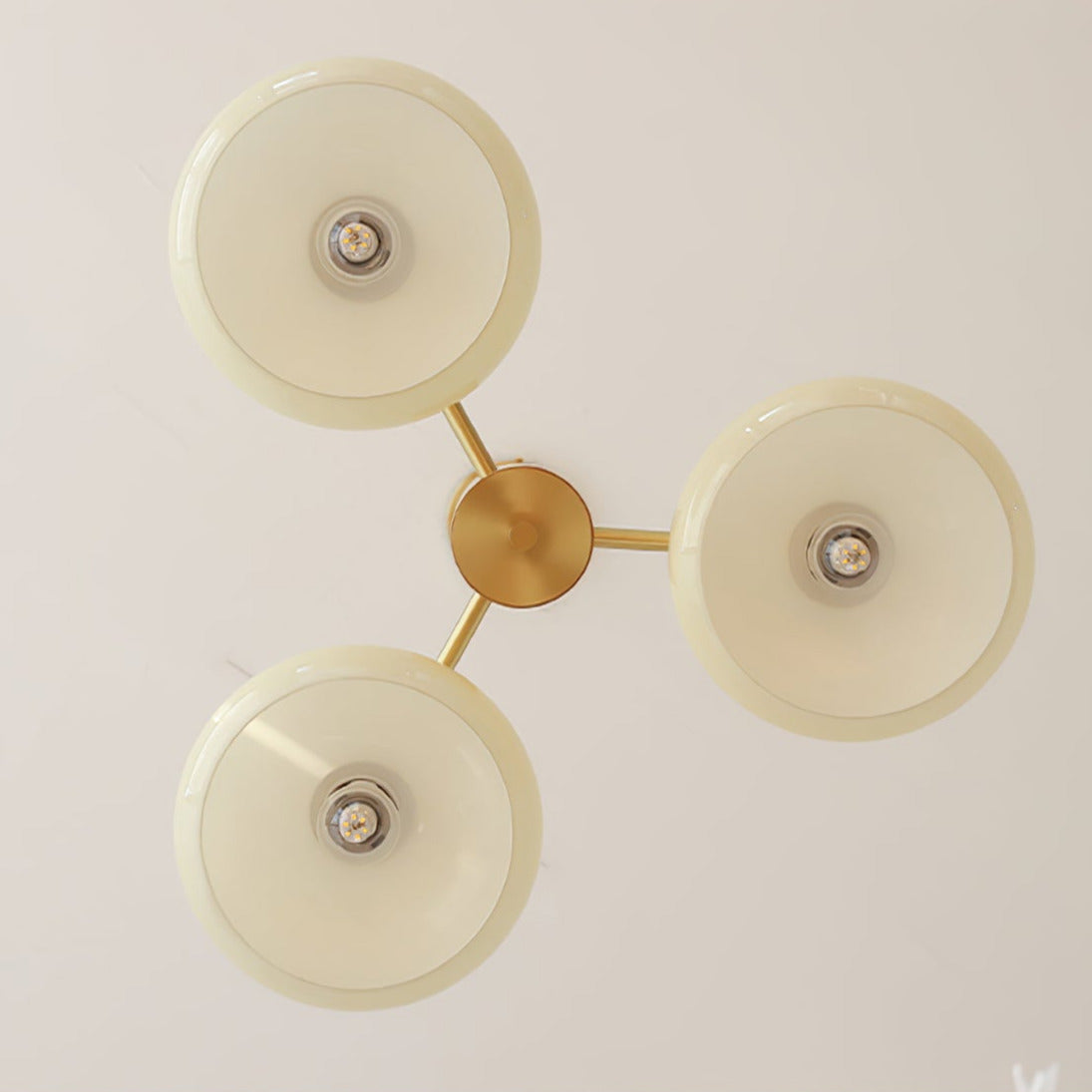 Seen from directly below, the Clérachic three-light chandelier shows three glass discs around a brass hub.