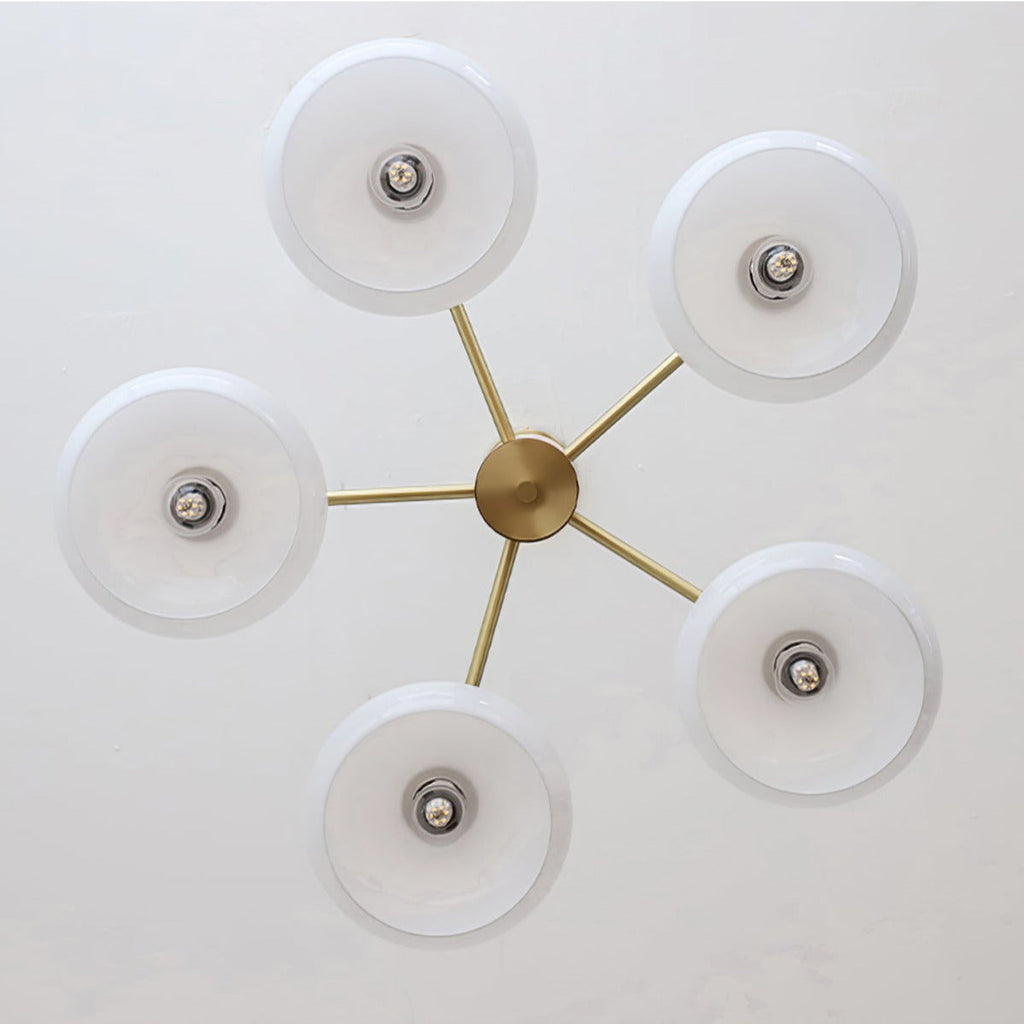 Underside view of the Clérachic five-light chandelier, white glass discs radiating from the brass centre hub.