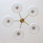 Underside view of the Clérachic five-light chandelier, white glass discs radiating from the brass centre hub.