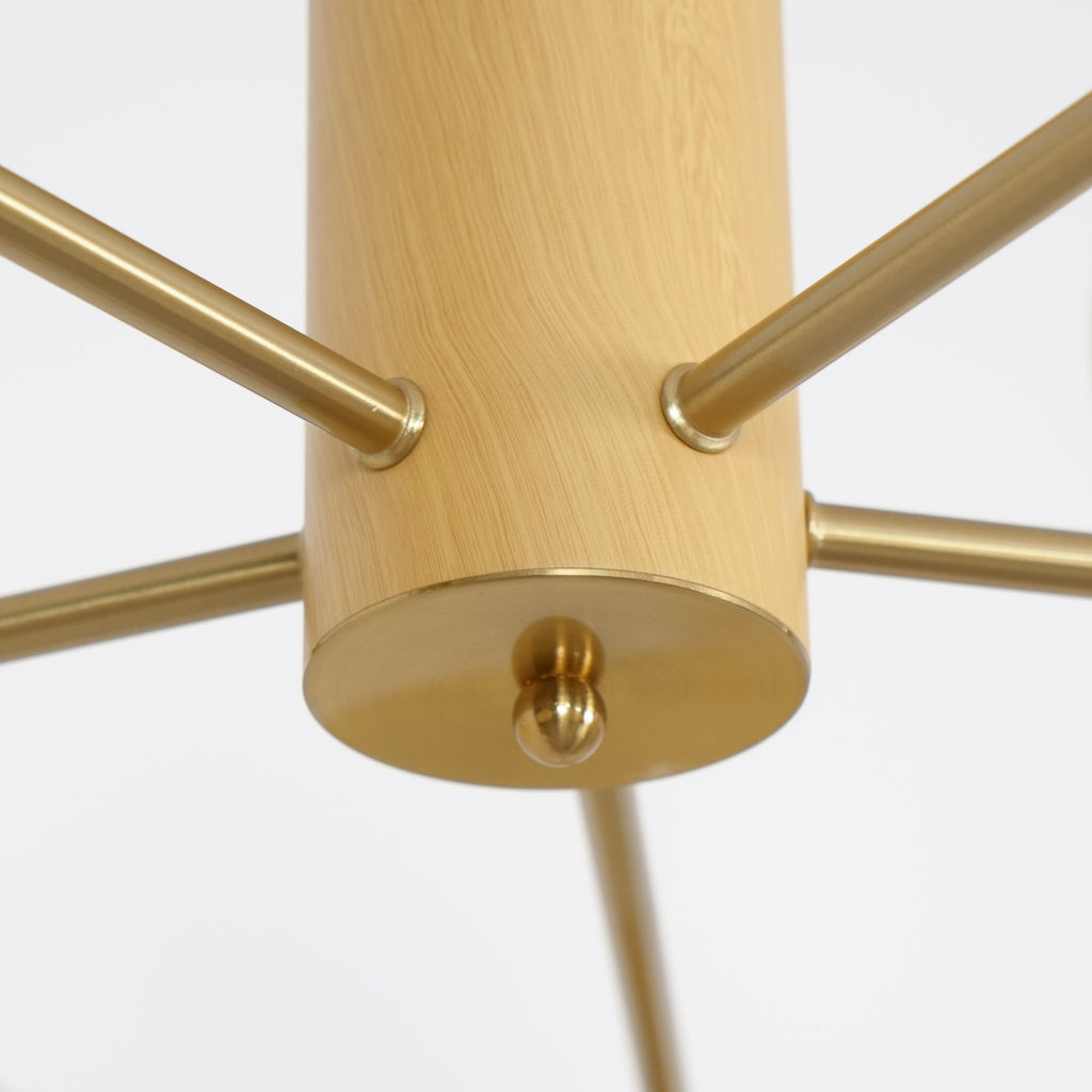 The brass ball finial under the wood cylinder of the Clérachic chandelier, with five rods radiating out.
