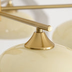 Macro of the brushed brass cone fitter meeting the glossy beige glass shade on the Clérachic chandelier.