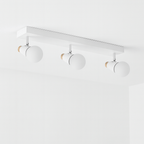 Clérachic white three-head ceiling spotlight bar with cone-shaped heads and wooden end caps, switched off on a white ceiling.