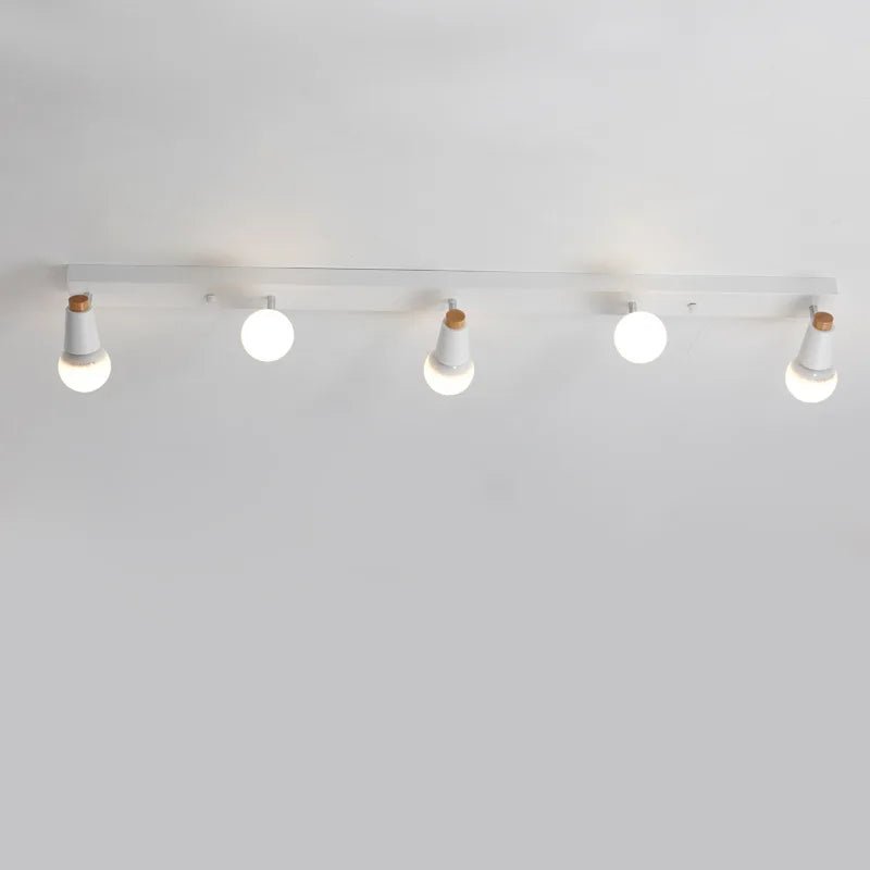 Clérachic long white five-head ceiling spotlight bar with globe bulbs lit, mounted along a plain ceiling in a room.