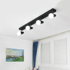 Clérachic black four-head ceiling spotlight bar with globe bulbs lit above a room with a landscape painting and shutters.