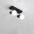Clérachic black two-head ceiling spotlight with glowing globe bulbs on a rectangular plate, studio shot on a pale ceiling.