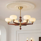 Below a ribbed white ceiling rose, this Clérachic chandelier hangs from a brass stem, its cream glass shades lit in a bright white room.