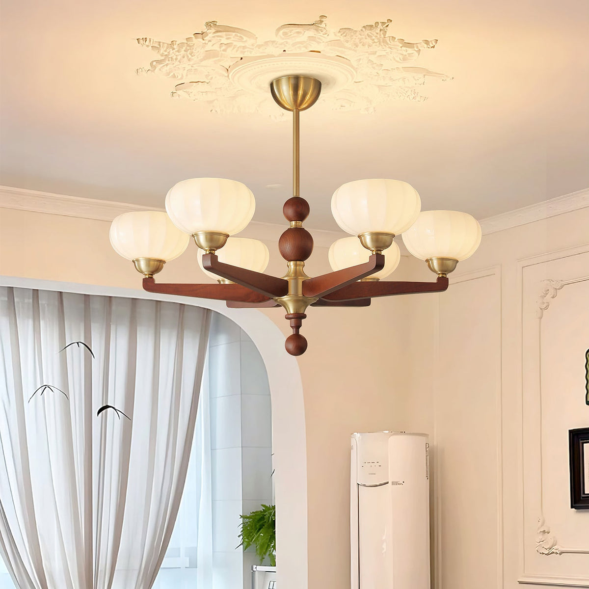 Warm light from the cream glass shades of this Clérachic chandelier fills a room with sheer curtains and cream wall panelling.