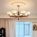 Seen from across the room, this Clérachic chandelier hangs low beneath a round ceiling rose, with a tall window and curtains behind.