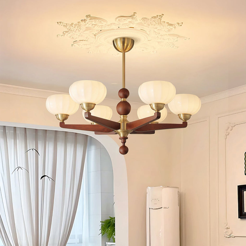 This Clérachic chandelier glows under a decorative plaster ceiling moulding, beside an arched doorway with long curtains.