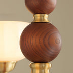 Close view of the grained walnut-coloured wood ball and brass collar on the stem of this Clérachic chandelier.