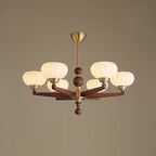 This Clérachic chandelier in its larger form, with six cream glass shades on turned wood arms, against a muted taupe backdrop.