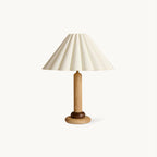 This Clérachic table lamp has a pleated cream shade on a slim wood stem and a rounded wooden base, shown on a plain white backdrop.