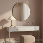 This Clérachic table lamp stands on a white console table under a round brass-framed mirror, with a pale pouffe below.