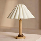 Close view of this Clérachic table lamp in natural wood, with a dark wood ring above the base and a wide pleated cream shade.
