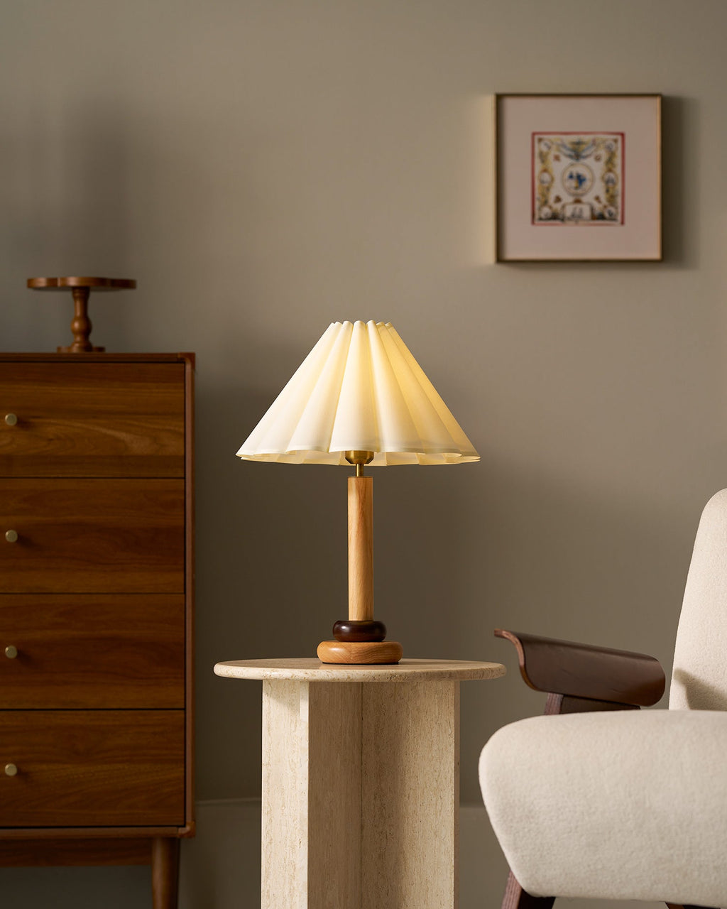 A smaller view of this Clérachic wood table lamp on a pale stone side table, with a framed print and tall chest of drawers beyond.