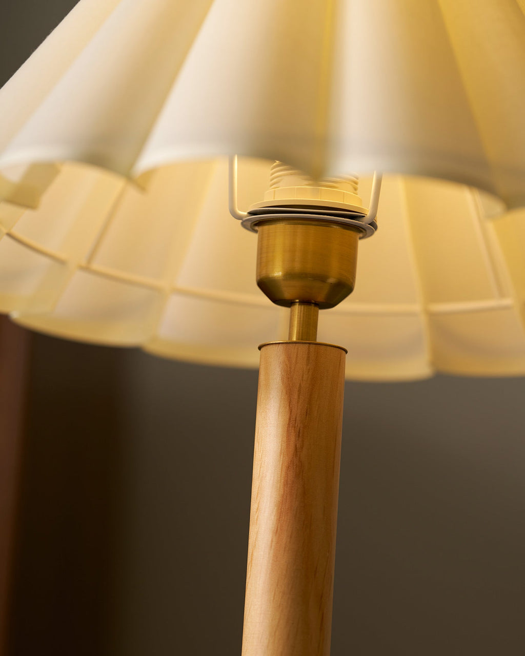 Close view from below of the brass bulb holder and the inner wire frame under the pleated shade of this Clérachic table lamp.