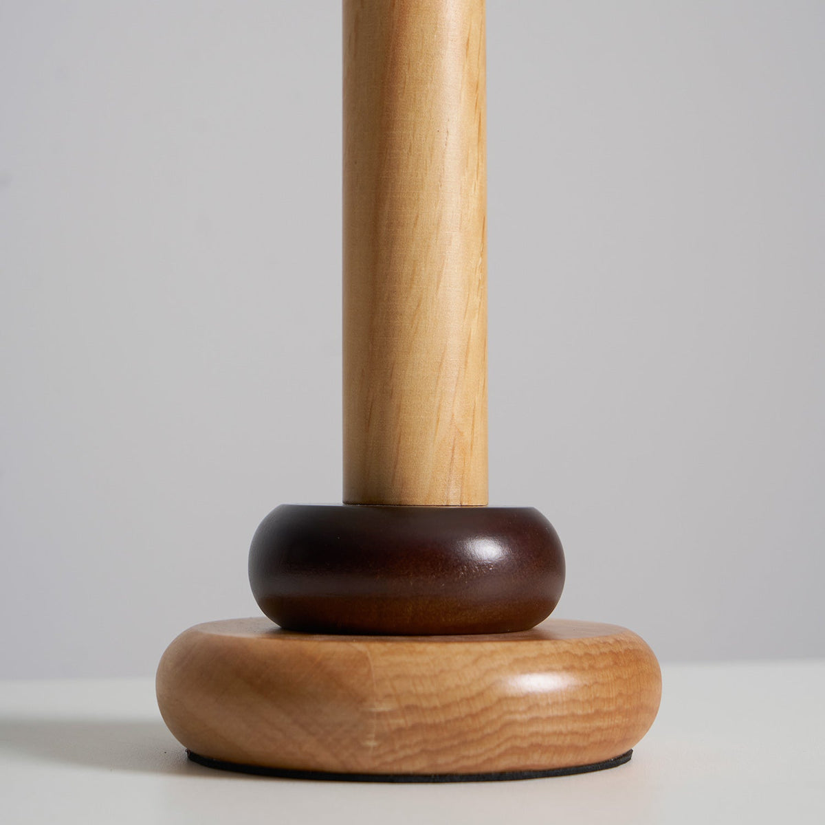Close view of the base of this Clérachic table lamp, with a dark wood ring sitting on a rounded natural wood foot.