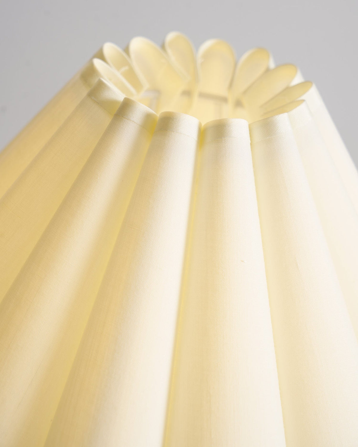 Looking up into the pleated cream shade of this Clérachic table lamp, where the fabric folds into a scalloped top rim.