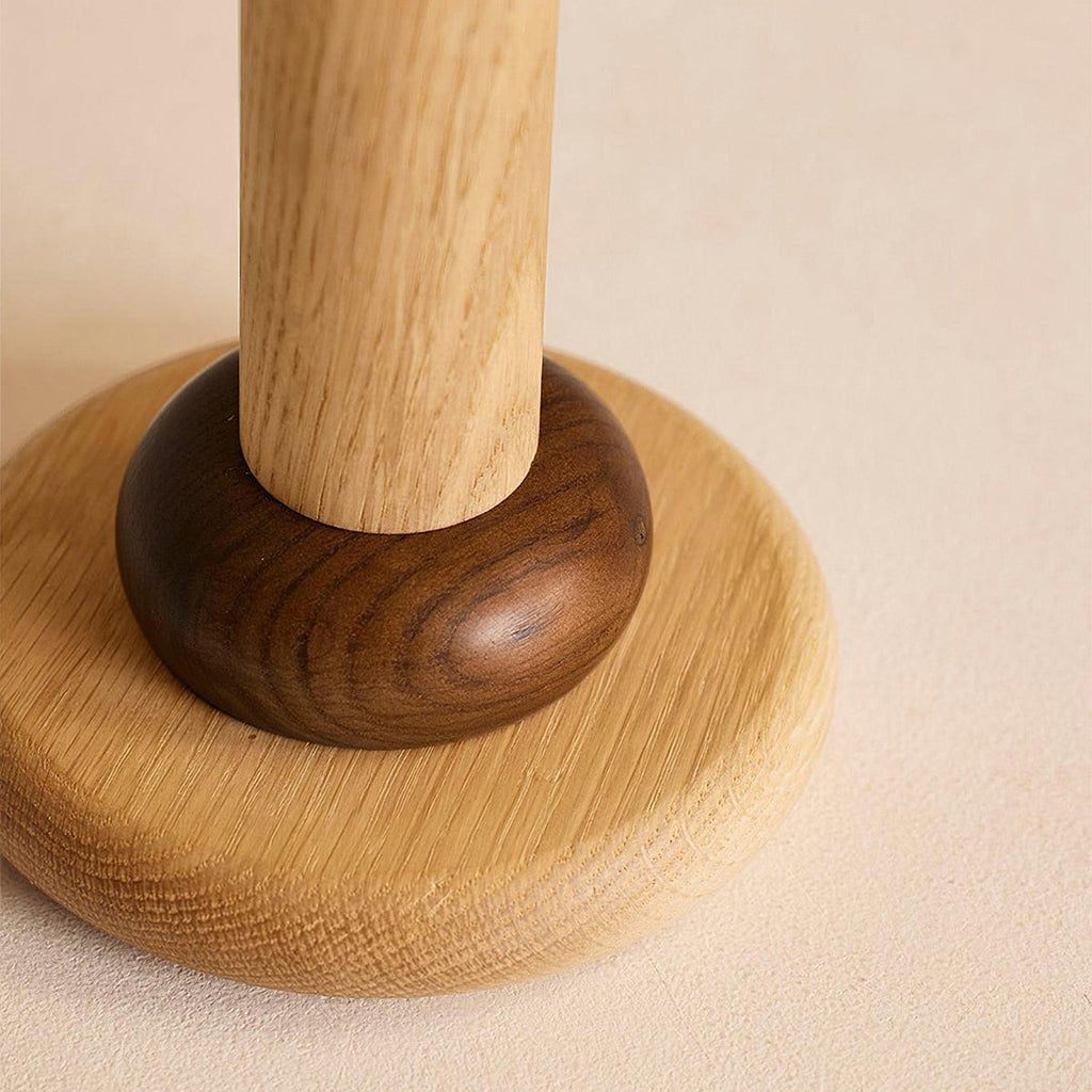 Close view of the wood grain on the stem, the dark walnut-toned ring and the round oak foot of this Clérachic table lamp.