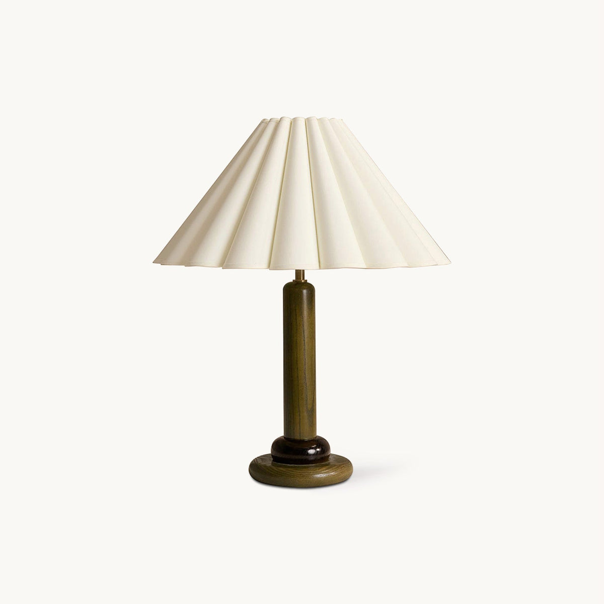 A Clérachic table lamp with a dark olive-green stem and base and a wide pleated cream shade, on a plain off-white backdrop.