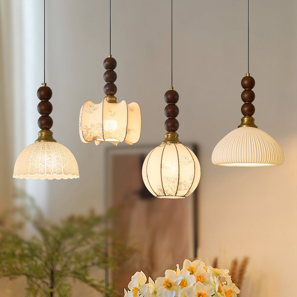 Four Clérachic pendants with different shade shapes hang side by side, each topped with stacked walnut beads.
