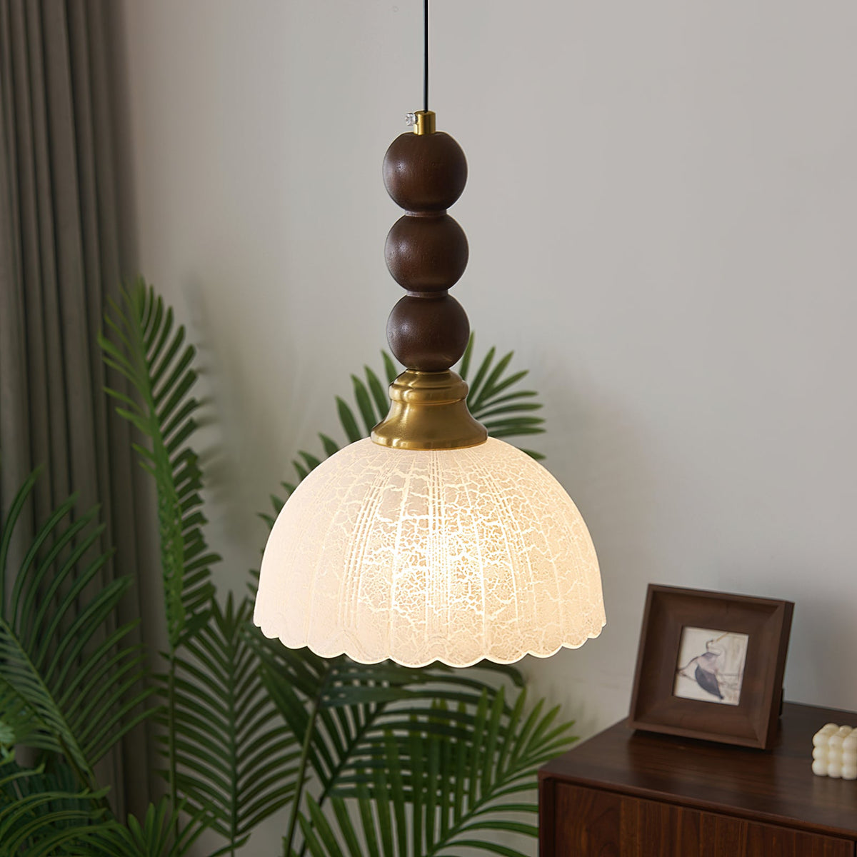 Close to a leafy green plant, this Clérachic pendant shows a frosted, crackle-patterned dome shade lit from within.