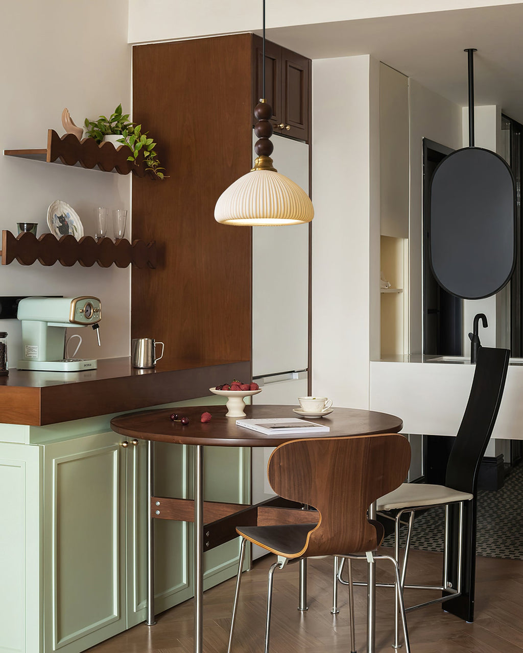 A ribbed ceramic Clérachic pendant hangs beside a brass-edged wooden shelf, above a walnut table and a mint kitchen unit.
