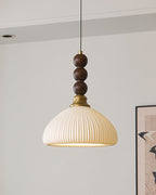 A ribbed cream ceramic shade on this Clérachic pendant, hung against a pale wall with a framed print at the edge.