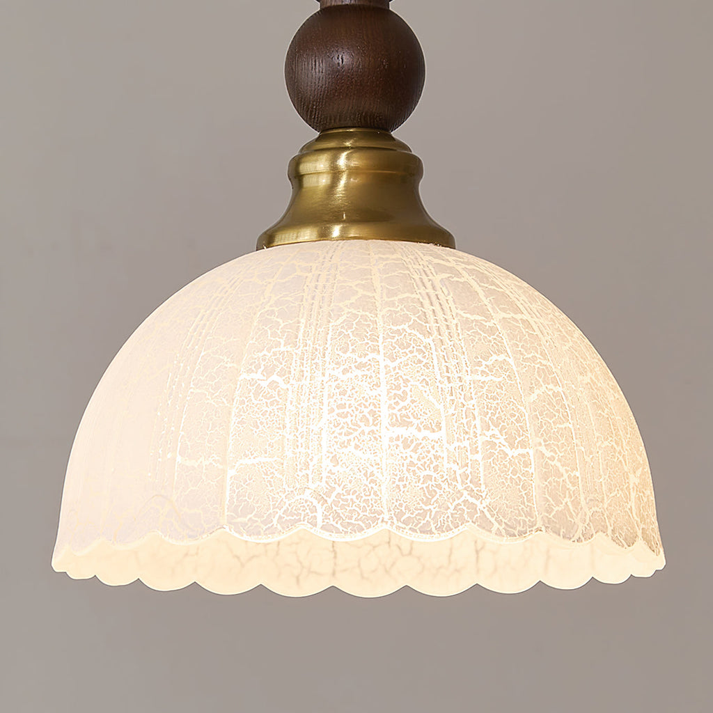 Close view of the frosted, scalloped-edge glass shade and brass collar on this Clérachic pendant.