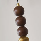 Close view of three stacked walnut wood beads and the brass fitting at the top of this Clérachic pendant.