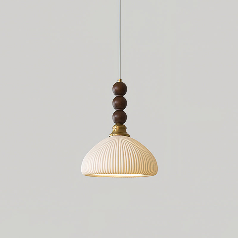 A ribbed ceramic Clérachic pendant with a brass collar and walnut beads, hung against a plain light grey wall.