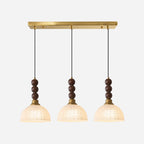 Three frosted-shade Clérachic pendants hang from one long brass bar canopy, each with stacked walnut beads.